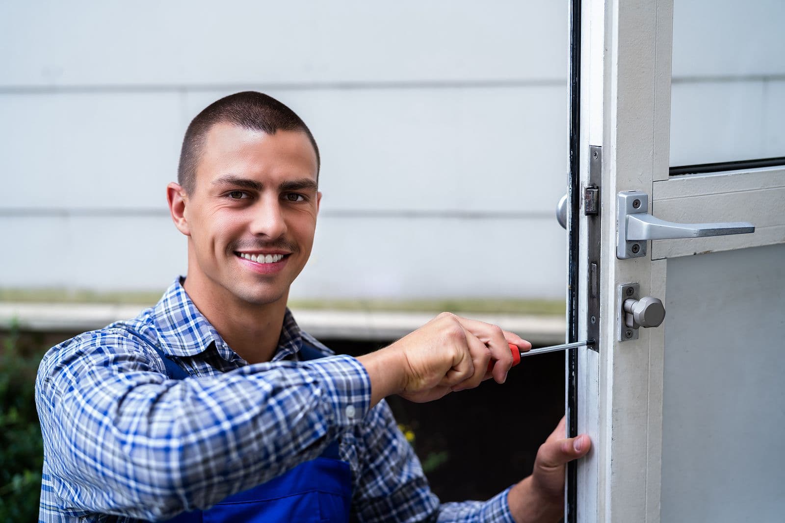 Workman fixing a door lock with a screwdriver.
